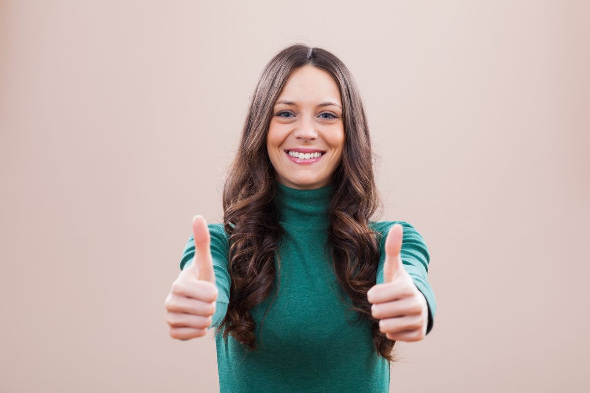 A smiling woman giving two thumbs up